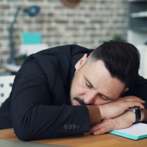 Väsinud mees magab laua peal — läbipõlemine, adrenaalne väsimus